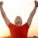 Junger Mann freut sich im Sonnenuntergang