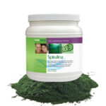 Spirulina-Pulver in Verpackung auf grünem Untergrund.