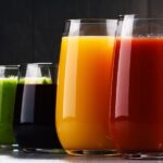 Vier Gläser mit Säften und Smoothies in den Farben rot, gelb-orange, grün und dunkelrot.