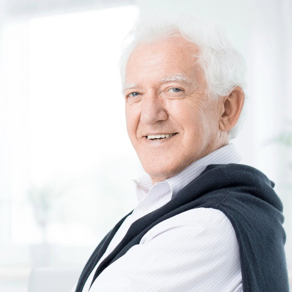 Freundlicher Rentner mit weißem Haar schaut zielstrebig in die Kamera.