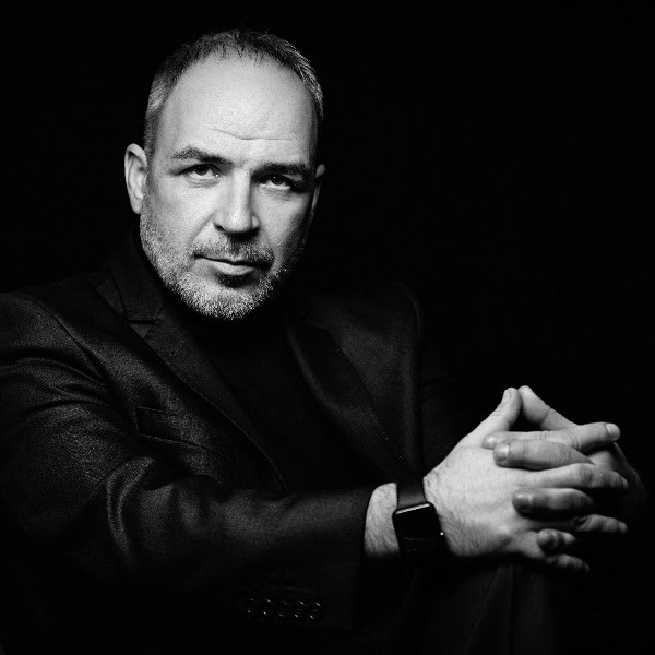 Älterer Mann im dunklen Anzug schaut gediegen in die Kamera.