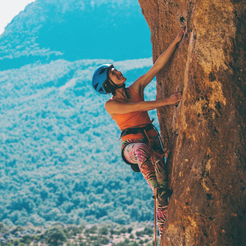 Frau klettert an steiler Felswand