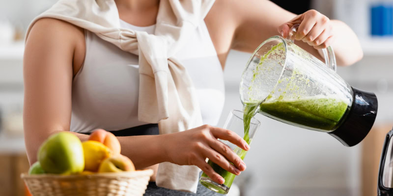 Grüner Smoothie wird in ein Glas gegossen.