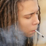 Junge mit Dreadlocks raucht einen Joint