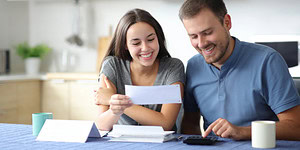 Lächelndes Paar mit Dokumenten am Tisch