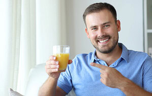 Mann hält ein Glas Orangensaft