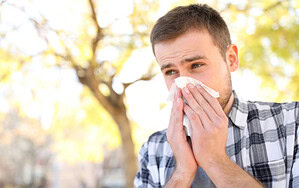 Mann putzt sich draußen die Nase