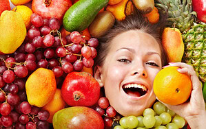Lächelnde Frau zwischen bunten frischen Früchten